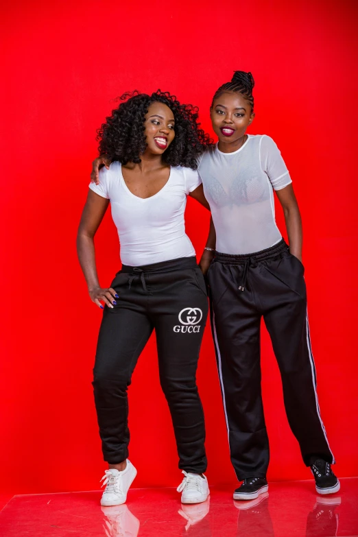 two young women pose for a picture in front of a red background