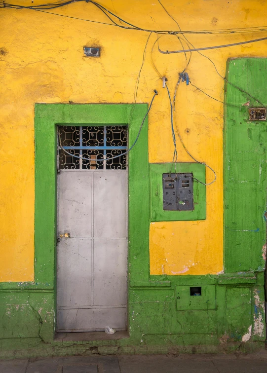 a yellow, green and gray building that has two windows