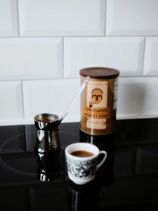 coffee cup and grinder on black table in front of white brick wall