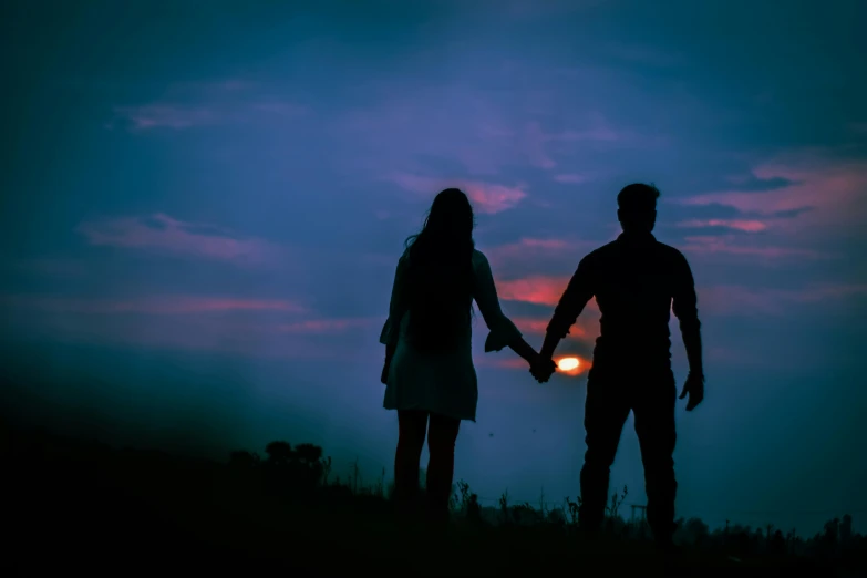 silhouette of two people holding hands at sunset