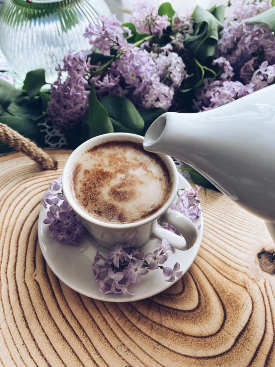 coffee with creamer on saucer surrounded by lavender flowers