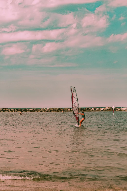 a person is windsurfing in the water near a rock wall