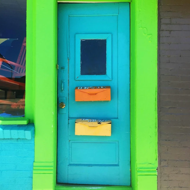 a bright blue and green door next to a brick building