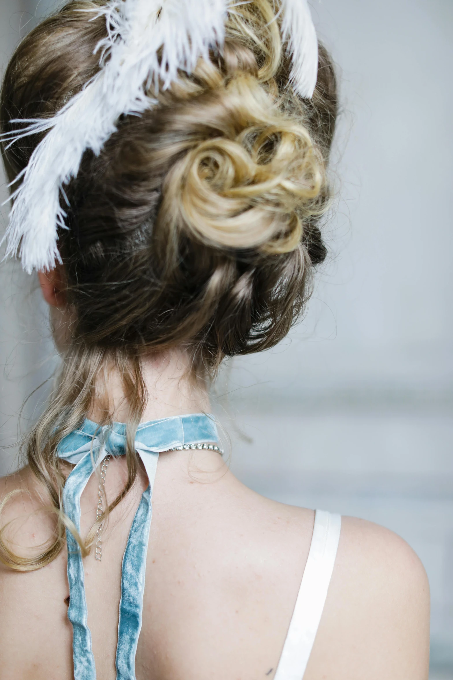 the back of a woman's head with a feather tied around it