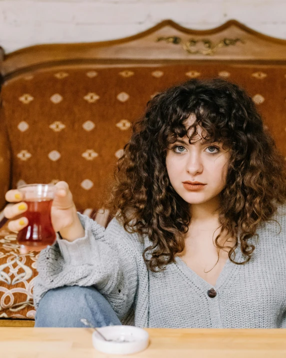 a close up of a person holding a drink near a couch