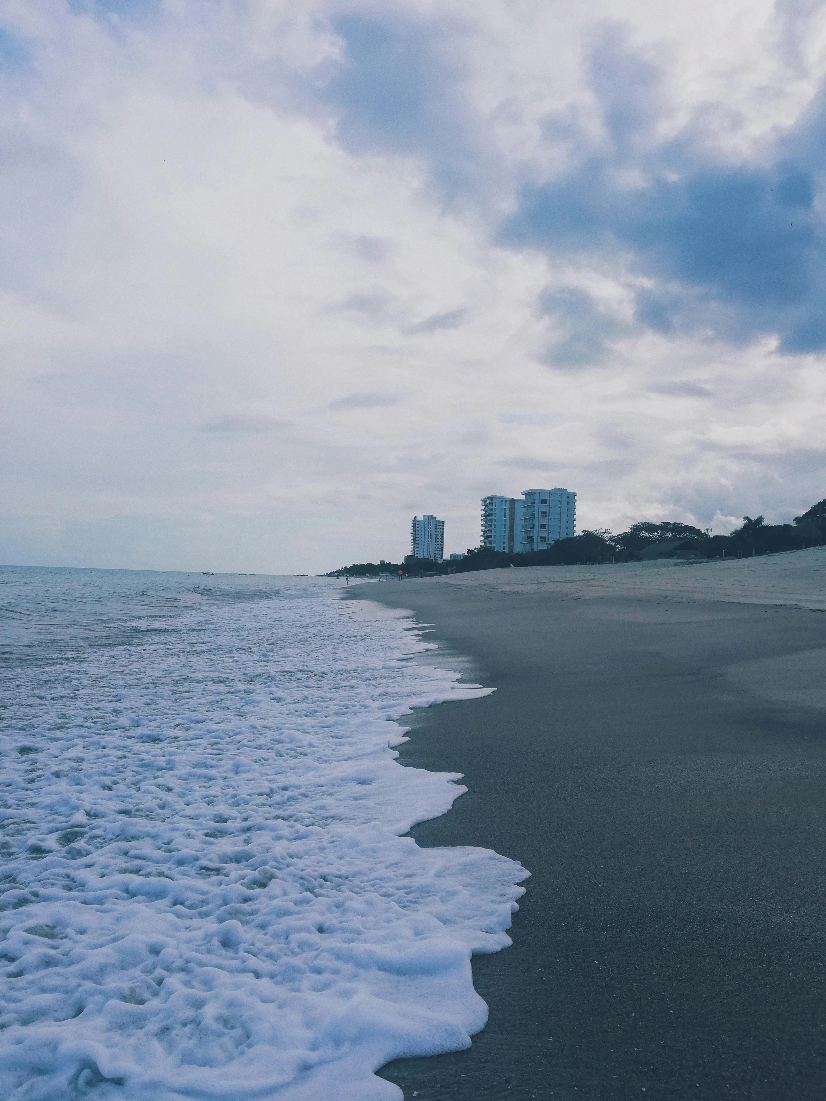 an empty beach and buildings with water coming off it