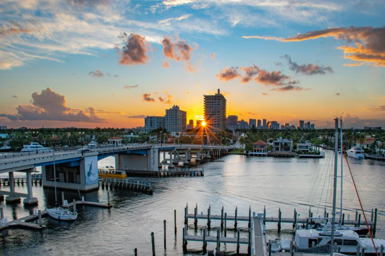 an orange sunset in front of a city with boats