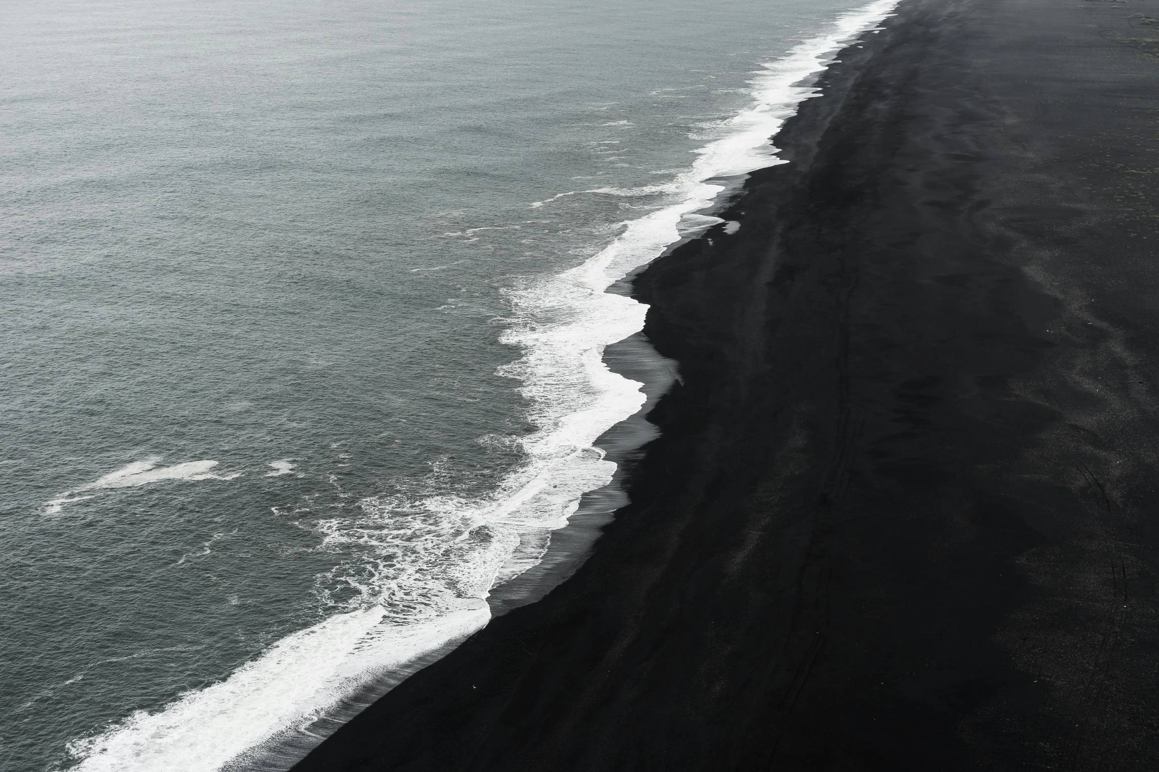 surfers and sand dunes at the beach with dark, low tide