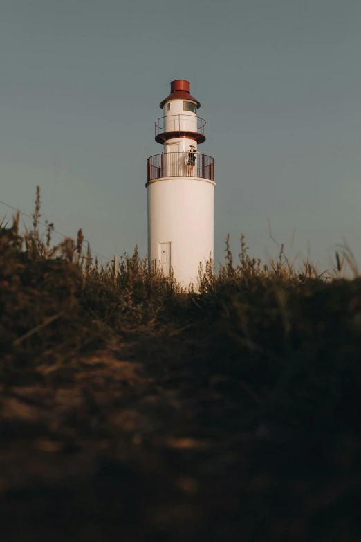 a light house sitting on top of a grass covered hillside