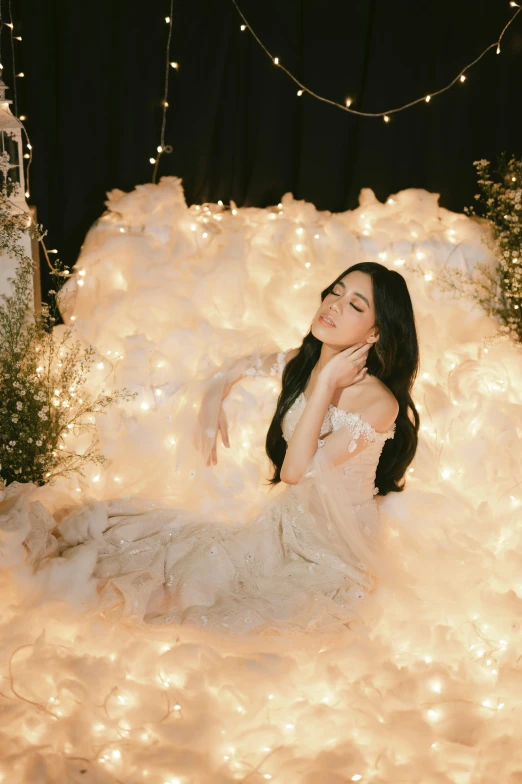 a woman with long dark hair sits on a fake foamed wall