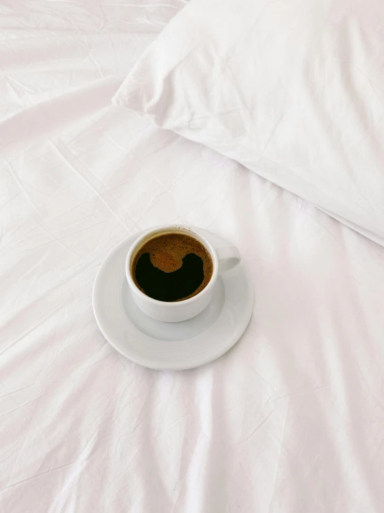 cup on a saucer in front of a white pillow