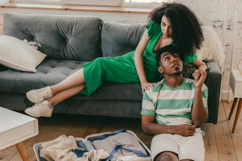 a woman sitting on the couch while the man holds the hair down