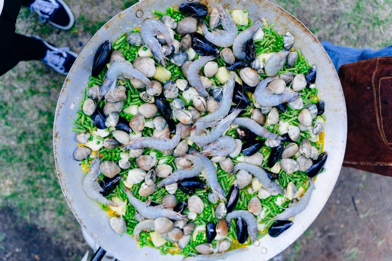 a dish of vegetables and sausages in sauce being held by a person