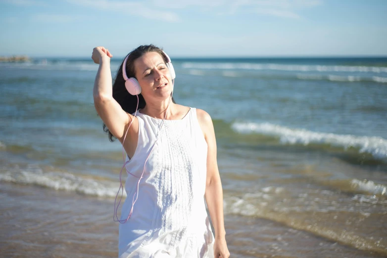 an image of woman listening to music on the beach