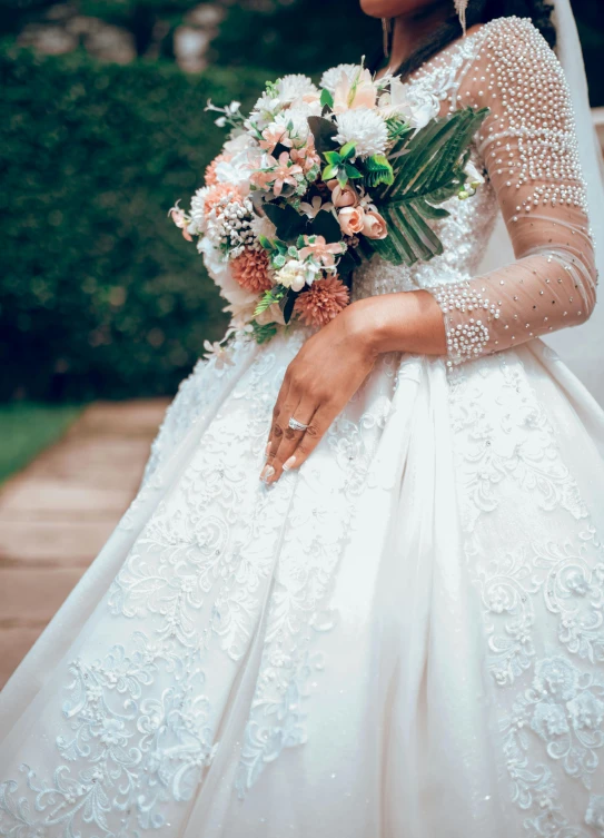 a woman wearing a wedding dress with long sleeves and flowers