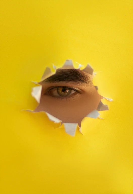 a person peeks through a hole in the paper