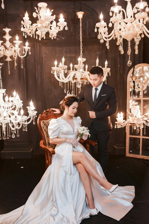 two people wearing gowns sitting near chandelier