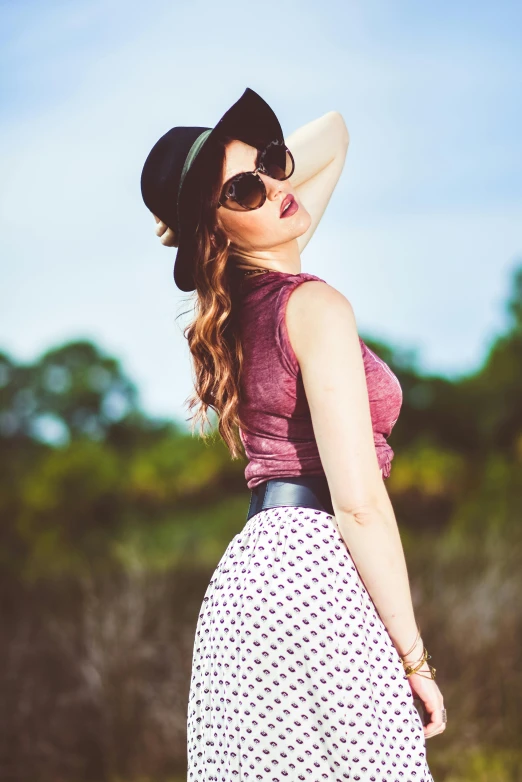 a woman wearing a hat and glasses standing outdoors