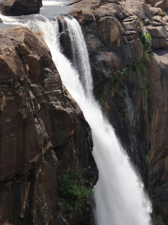 a waterfall next to the rocks near some trees