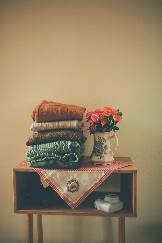 a pile of towels, two vase and a stack of folded cloth on a table