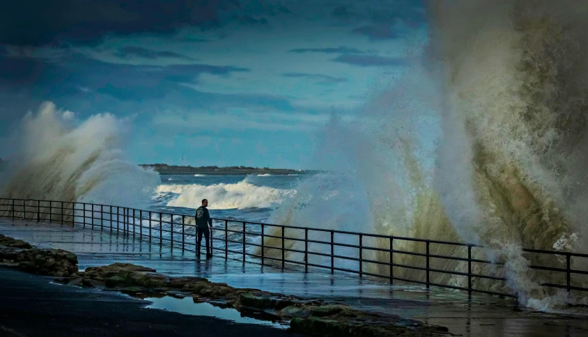 a man standing on the beach next to a pier covered in water