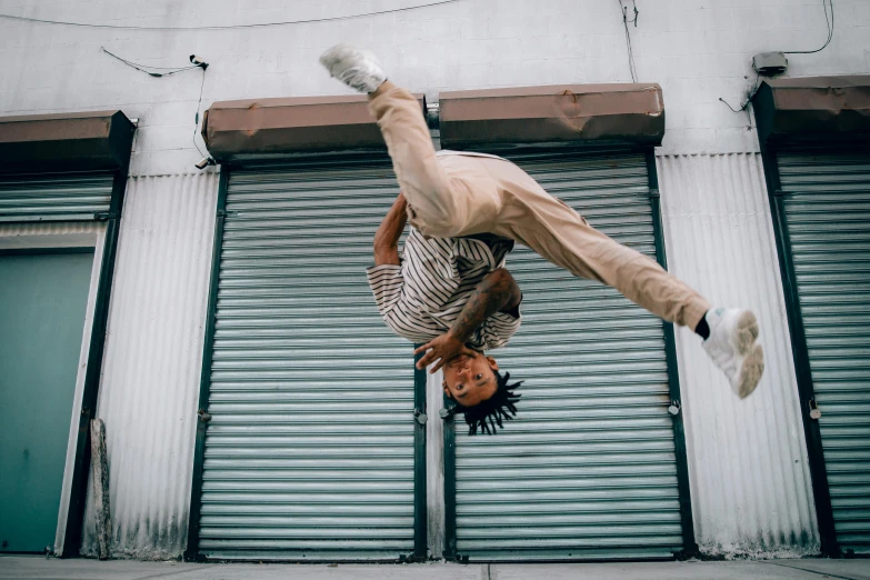 man doing acrobatic trick on street outside building