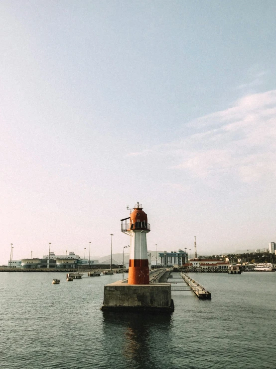 a small light tower in the water with people around