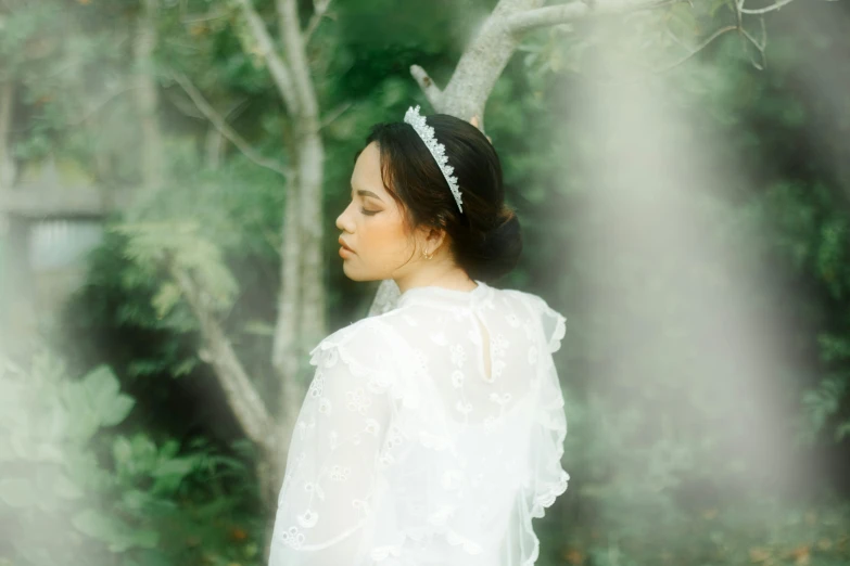 a woman is standing in the woods wearing a wedding veil
