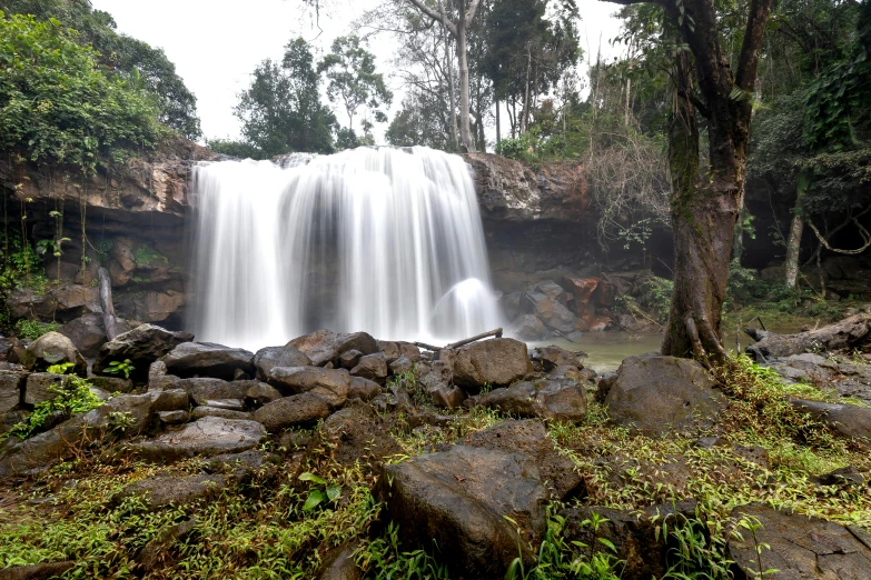 a water fall surrounded by rocks and lush green foliage