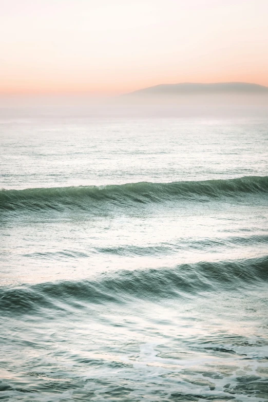 a person is standing on a surfboard near the beach