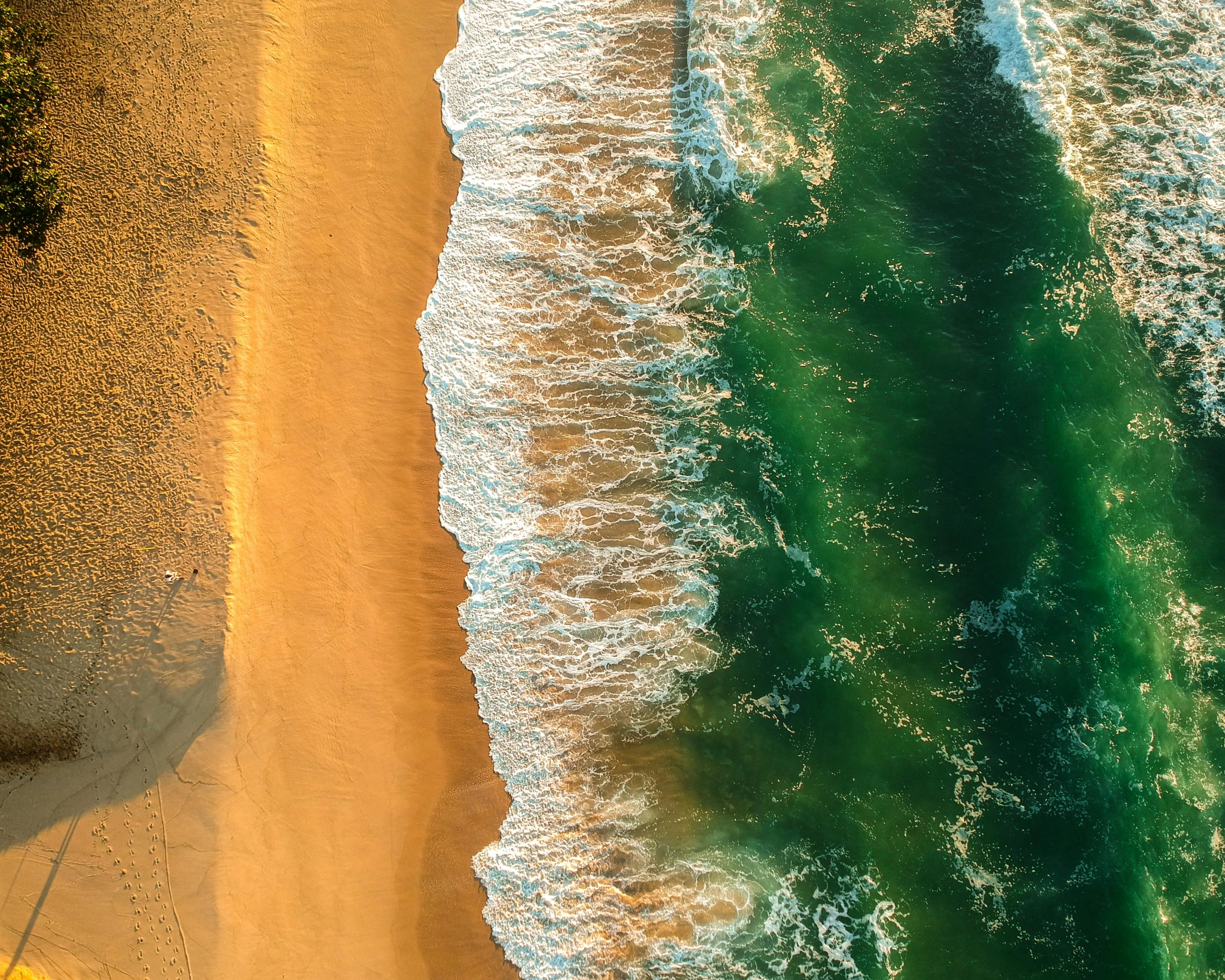 the waves of the ocean are crashing onto a sandy beach