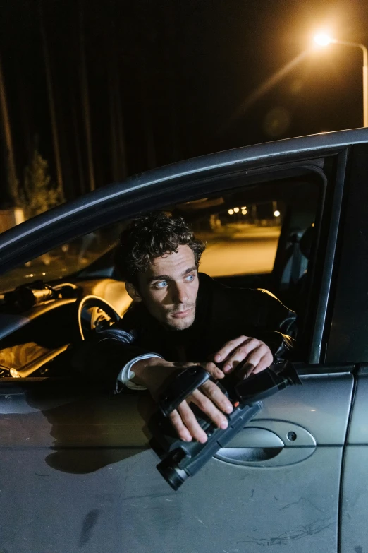 a man sitting in a car at night holding a remote control