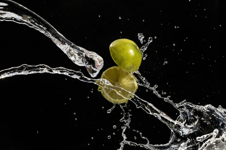 a lemon splashing in to water with another green one on the side