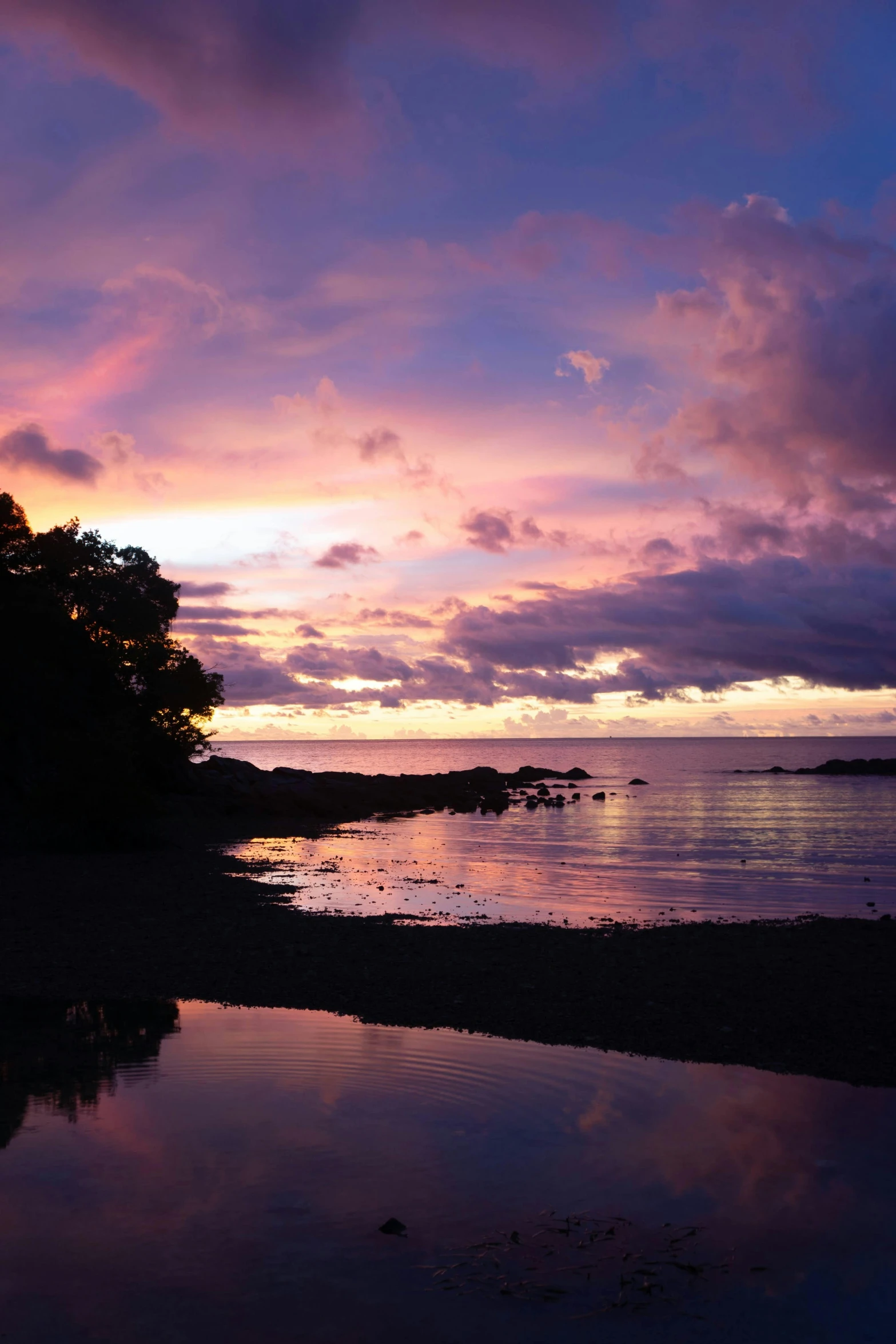 the sun sets at a beach, and it's reflection is in the water