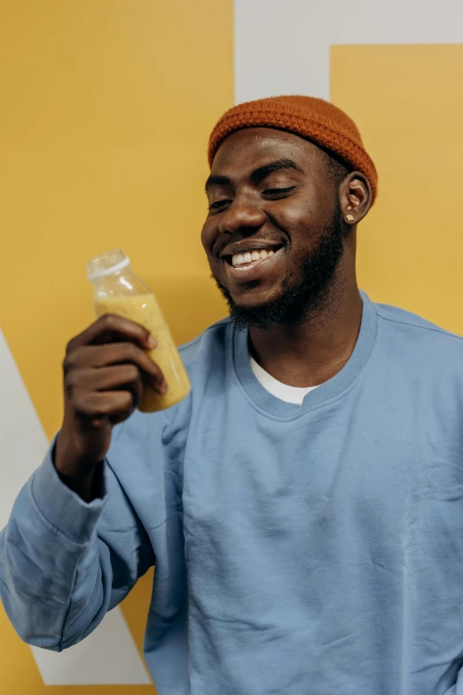 a man holding up a bottle in his left hand and the container he holds