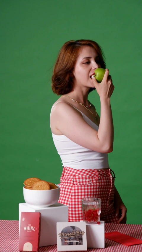 a woman sitting at a table holding an apple