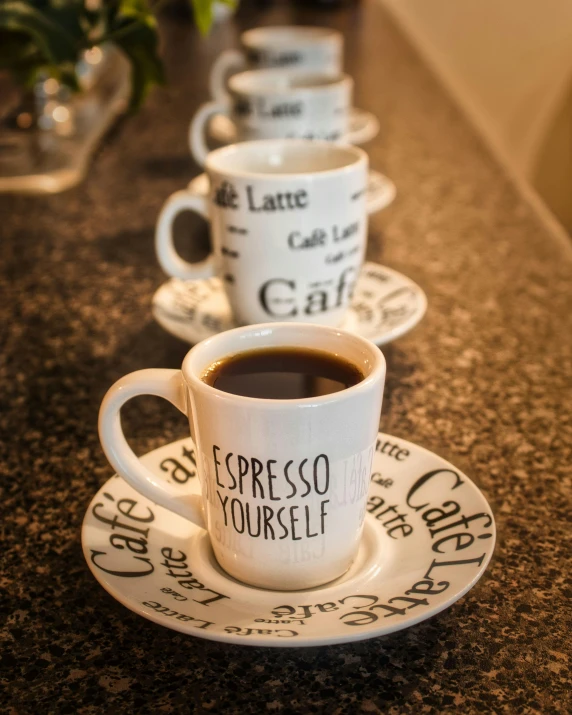 a line up of coffee cups and saucers that read espresso yourself