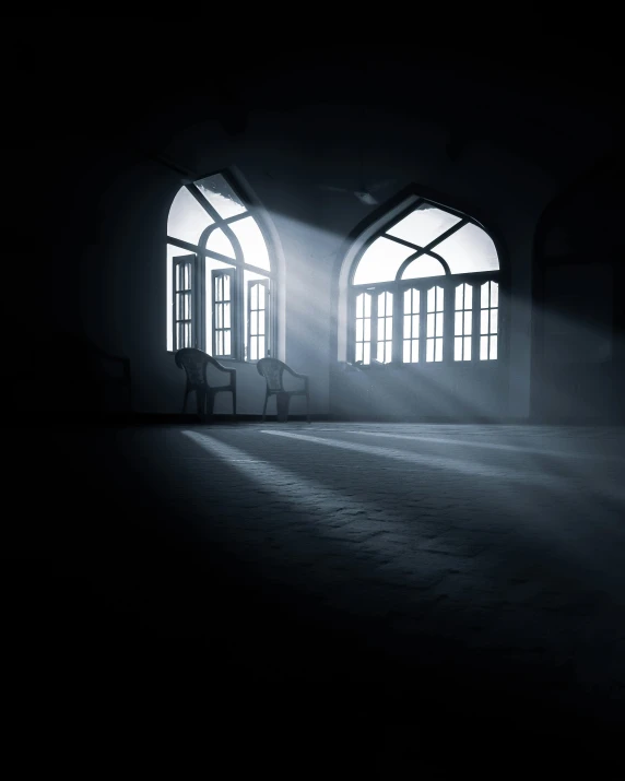 a dark room with large windows and light coming from it
