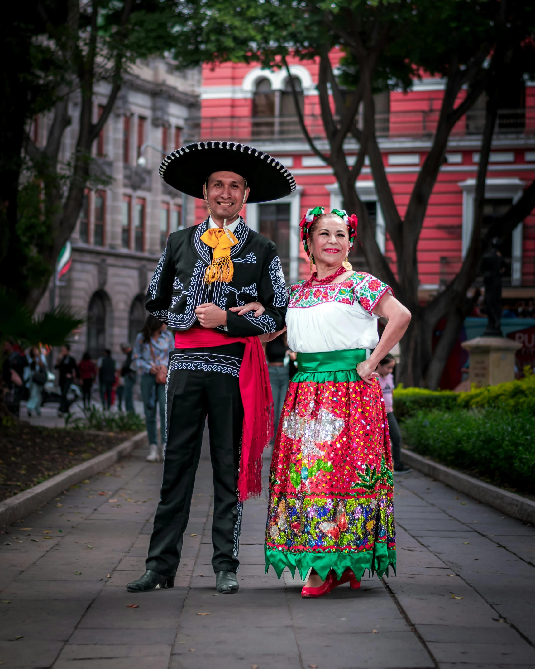 a man and woman in mexican attire stand on a city street