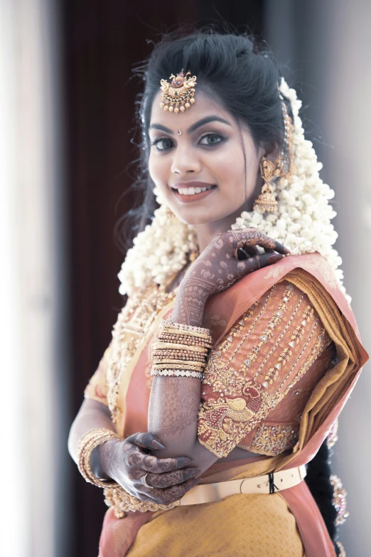 indian bridal standing and smiling while wearing an indian outfit