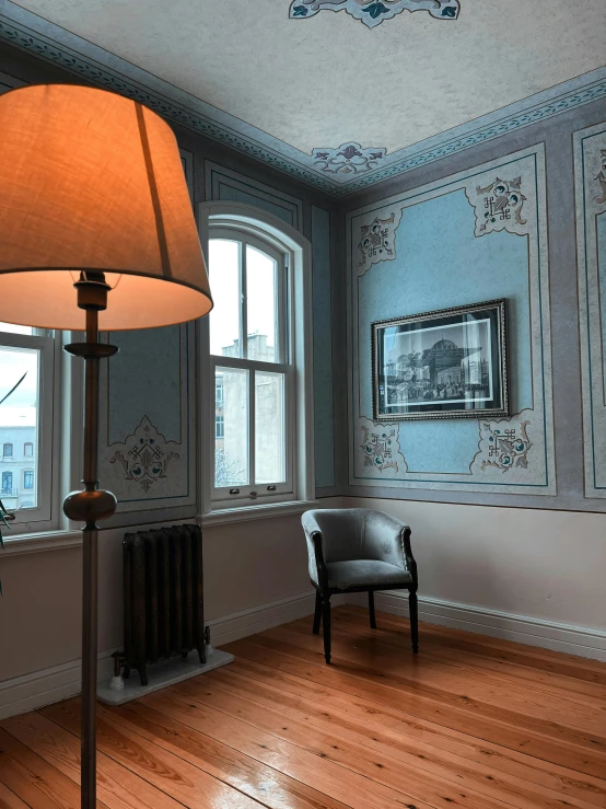 a room with blue walls, a lamp, and a chair