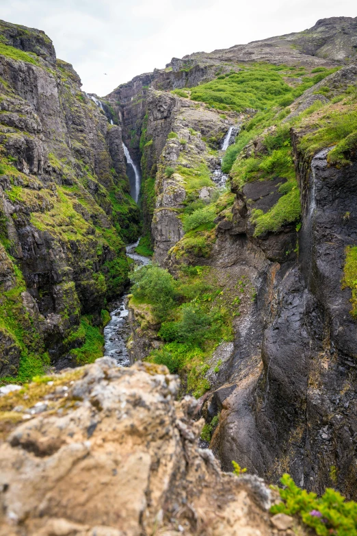 an area with large rocks, steep and rocky slopes and a small waterfall