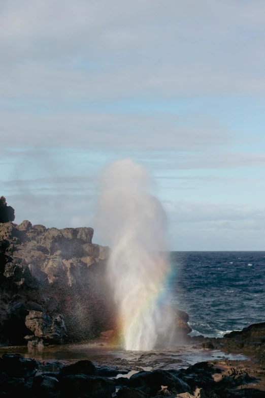 a rainbow coming out of the ocean with clouds