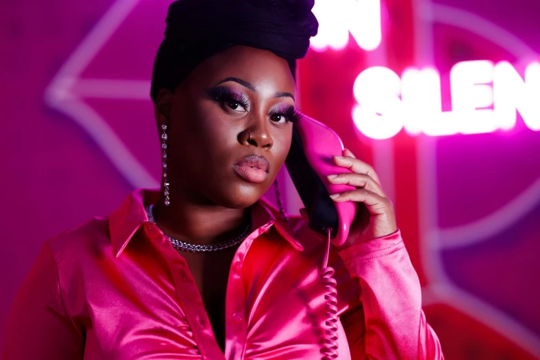 an attractive woman wearing a pink top, holding up a phone