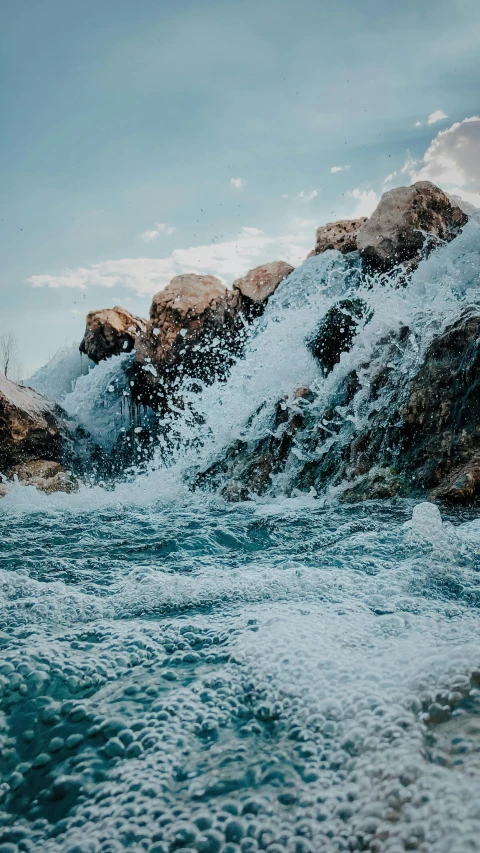 the blue water is flowing toward rocks with snow capped mountains in the distance