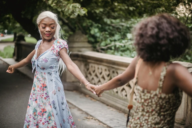 two women in dress walking and holding hands