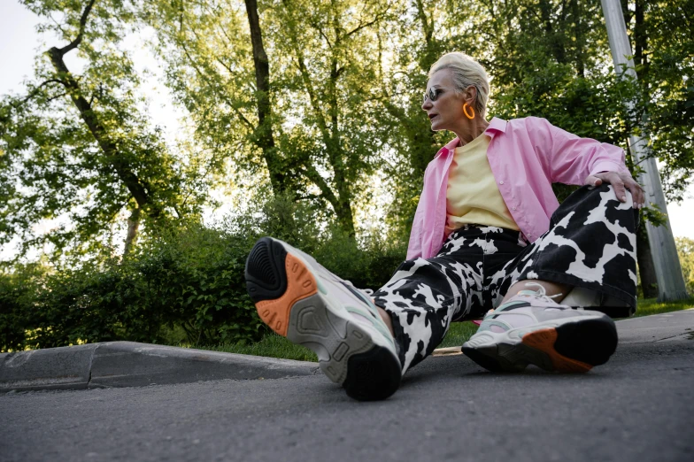 an elderly woman sits on the sidewalk and looks off to her right