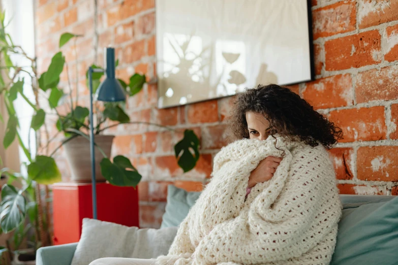 a woman wrapped in a blanket sitting on a couch