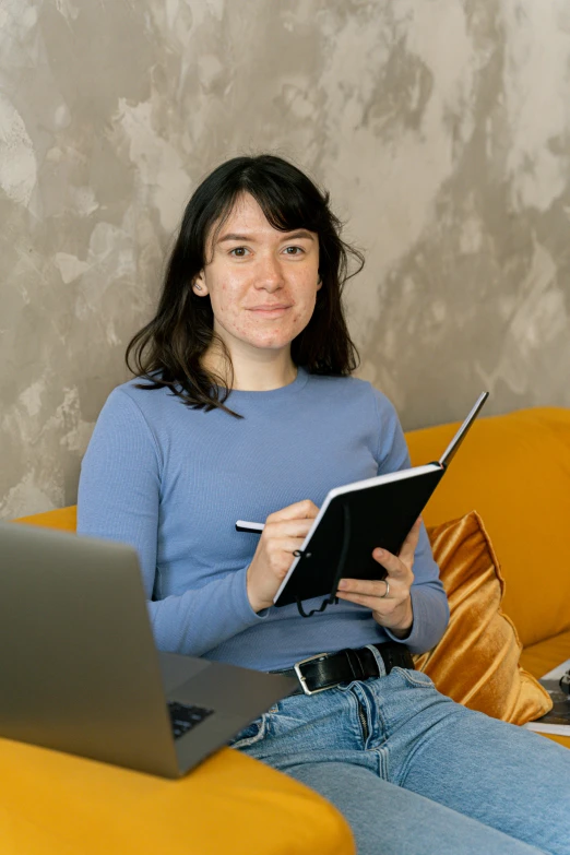 woman sitting in chair looking at camera with laptop nearby