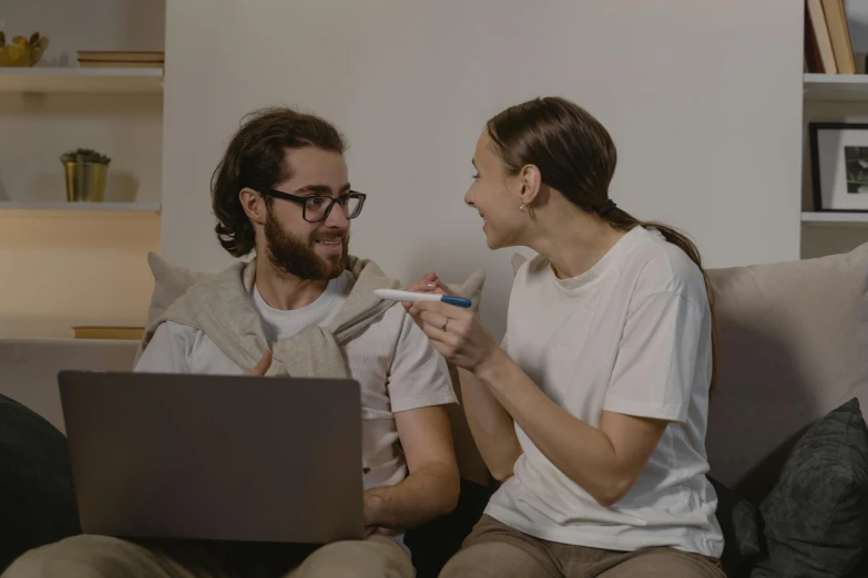 the woman holds a toothbrush and checks on her husband